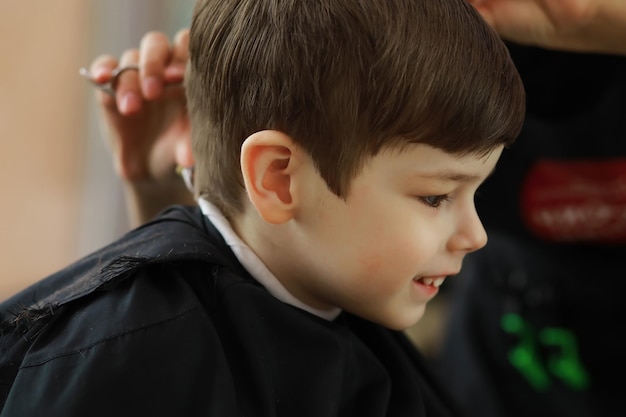 Knappe jongen die zijn haar en baard laat knippen bij kapperszaak, kapperszaak achteraanzicht