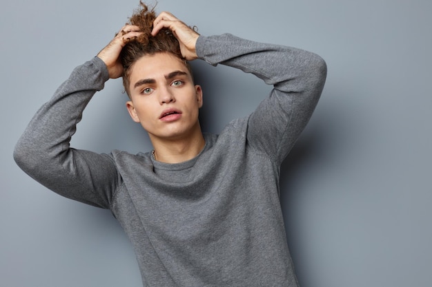 Knappe jongen in een grijze sweatshirt mode studio levensstijl ongewijzigd