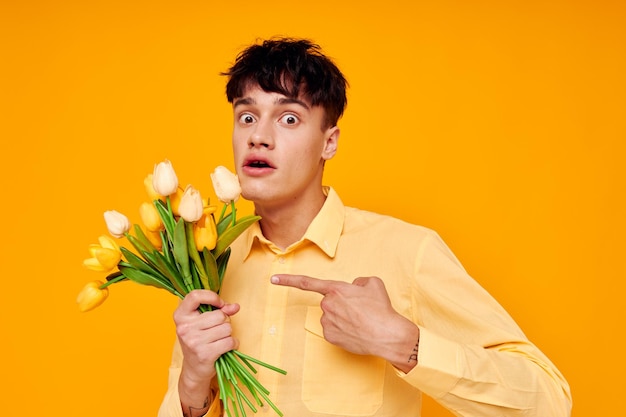 Knappe jongen in gele bril met een boeket bloemen gele achtergrond ongewijzigd