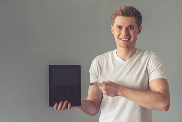 Knappe jongen in wit t-shirt toont een digitale tablet