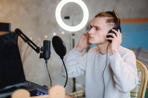 Knappe jongen neemt podcast op met behulp van microfoon en maakt inhoud voor audioblogman op