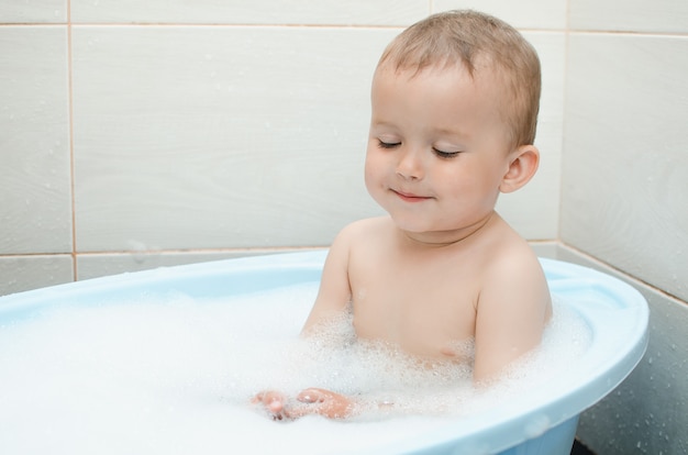 Knappe jongen peuter badend in de badkamer schoon en hygiënisch