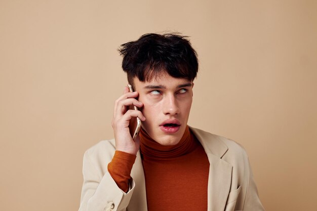 Knappe jongen poseren met een telefoon in zijn handen in een jas elegante stijl Lifestyle ongewijzigd