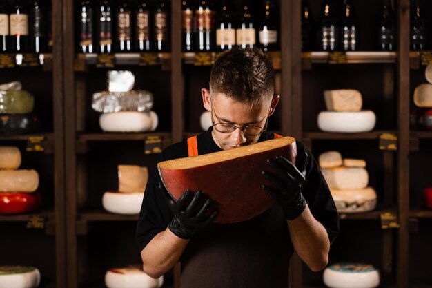 Knappe kaassommelier die beperkte Goudse kaas vasthoudt en snuift Snack lekker stukje kaas als voorgerecht