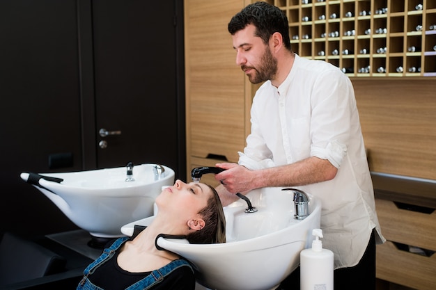 Knappe kapper vrouwelijk haar met concentratie wassen