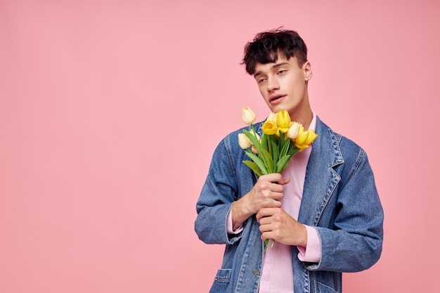 Knappe kerel boeket gele bloemen cadeau vakantie elegante stijl roze achtergrond ongewijzigd