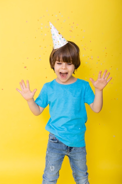 Knappe kleine feestvarken in blauw shirt en muts met ballonnen gele achtergrond gelukkige verjaardag