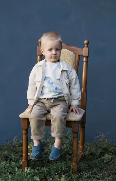 Knappe kleine jongen op stoel op blauwe achtergrond