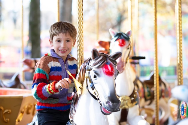 Knappe kleine jongen rijdt op een carrousel Een kind op een paardencarrousel