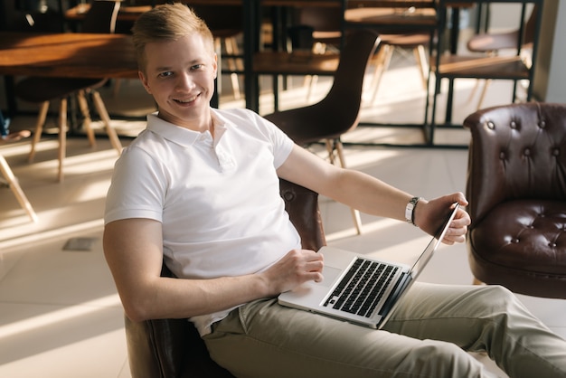 Knappe knappe jonge zakenman die met een laptop werkt