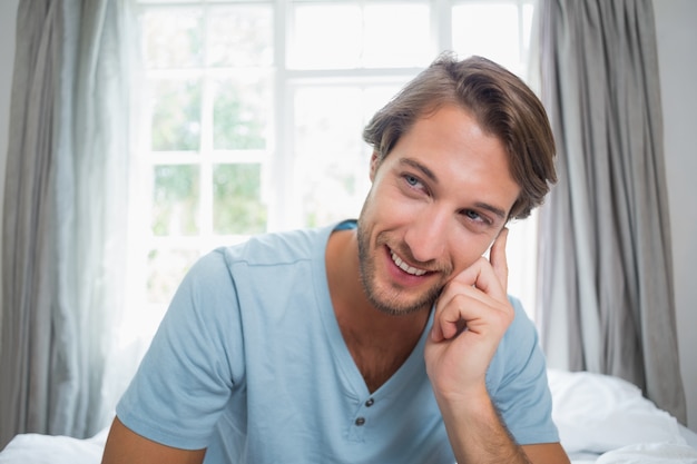 Knappe lachende man zittend op bed