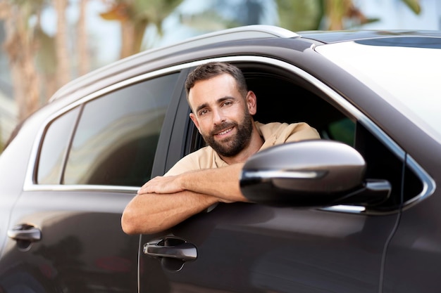 Knappe Latijns-rijdende zittend in de auto. Vervoersconcept. Succesvolle man die nieuwe auto koopt