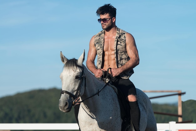 Knappe Macho Man Cowboy rijden op een paard Achtergrond van lucht en bergen