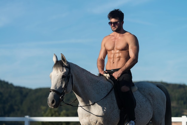 Knappe Macho Man Cowboy rijden op een paard Achtergrond van lucht en bergen