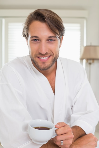 Knappe man aan het ontbijt in zijn badjas koffie drinken