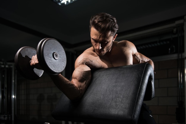 Knappe Man Biceps Uitwerkend In Een Donkere Gym Halter Concentratie Krullen