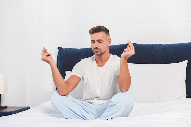 Knappe man die yoga beoefent in de slaapkamer