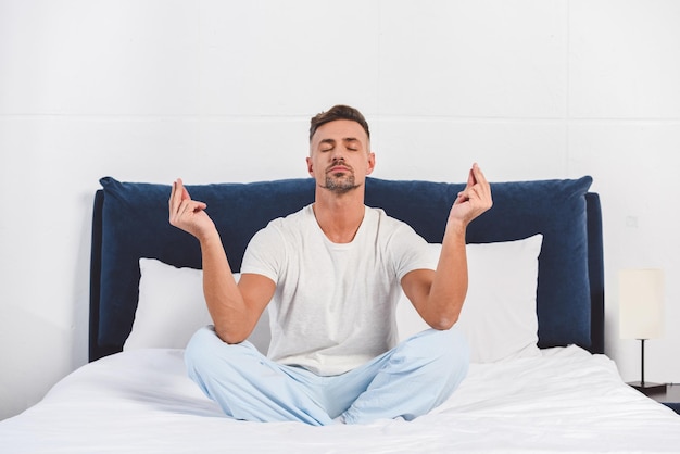 Knappe man die yoga beoefent in pyjama