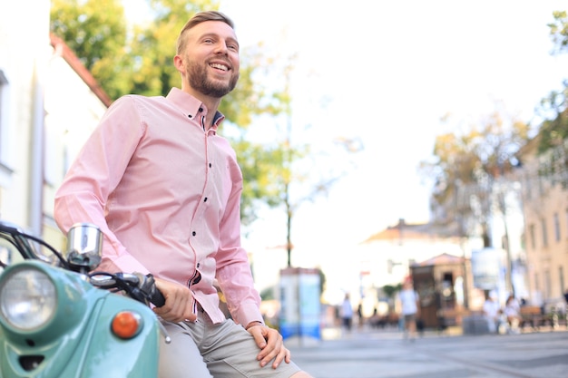 Knappe man die zich voordeed op een scooter in een vakantiecontext. Straatmode en stijl.