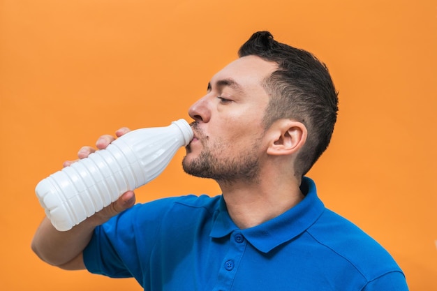 Knappe man drinkt yoghurt of melk op oranje achtergrond Mock up kopie ruimte