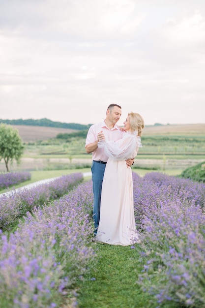 Knappe man en elegante mooie blonde dame, daten en samen wandelen buiten in lavendelveld