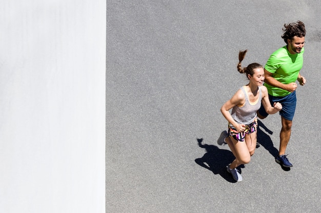 Knappe man en mooie vrouw joggen samen op straat op zonnige dag