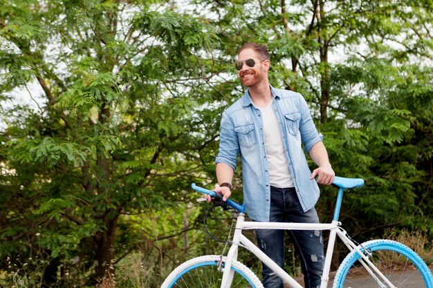 Knappe man genieten met zijn fiets in het park