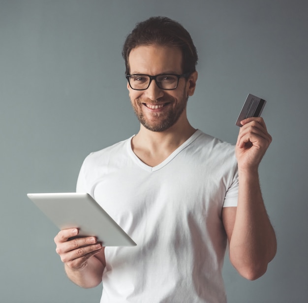 Knappe man houdt een digitale tablet en een creditcard