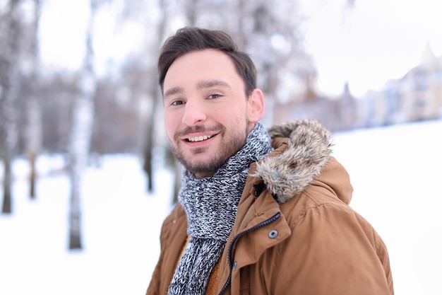 Knappe man in besneeuwd park op wintervakantie