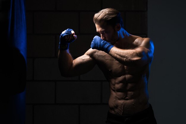 Knappe man in blauwe bokshandschoenen Boksen in de sportschool Het concept van een gezonde levensstijl Het idee voor de film over boksen