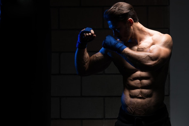 Knappe man in blauwe bokshandschoenen Boksen in de sportschool Het concept van een gezonde levensstijl Het idee voor de film over boksen