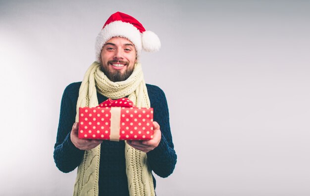 Knappe man in een kerstmuts met geschenken op een witte achtergrond.