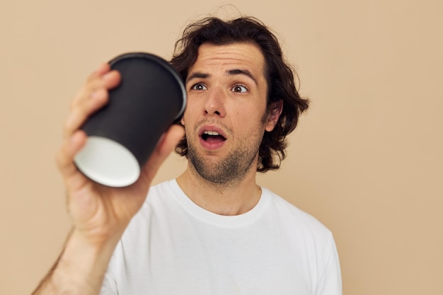 Knappe man in een wit T-shirt met een zwart glas in de hand Ongewijzigde levensstijl