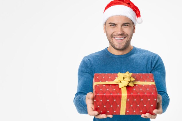 Knappe man in kerstmuts met geschenkdoos geïsoleerd op witte achtergrond