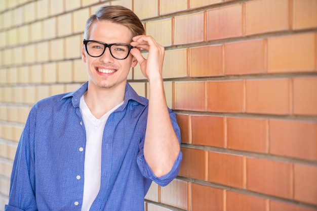 Knappe man in slimme vrijetijdskleding op bakstenen muur.