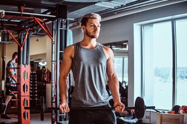 Knappe man in sportkleding doen oefening met een barbell in de fitnessclub of sportschool.