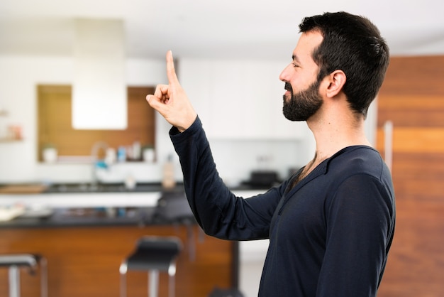 Knappe man met baard aan het raken op het transparante scherm in het huis