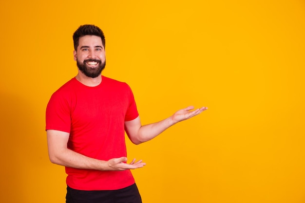 Knappe man met baard wijzend naar de zijkant glimlachend kijkend naar de camera.