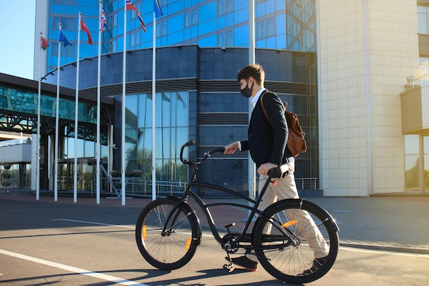 Knappe man met beschermend masker fietsen om werk te vinden.