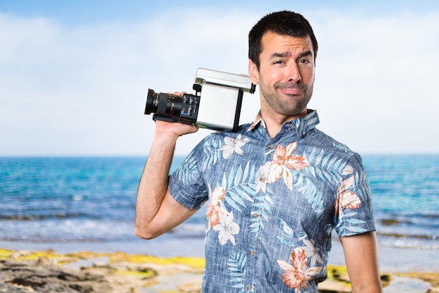 Knappe man met bloem shirt filmen op het strand