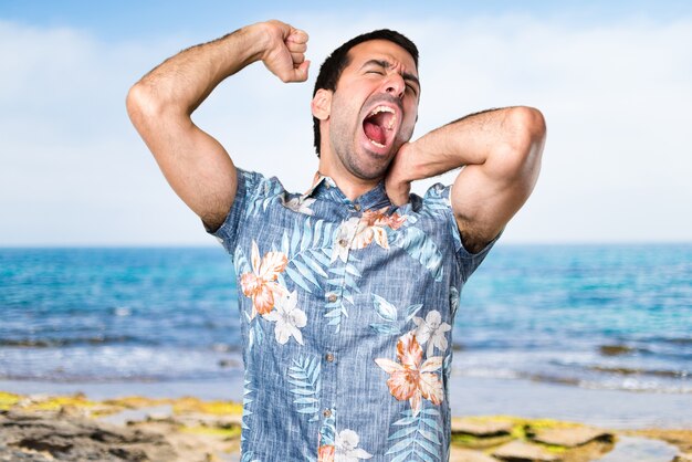 Knappe man met bloem shirt gauw op het strand