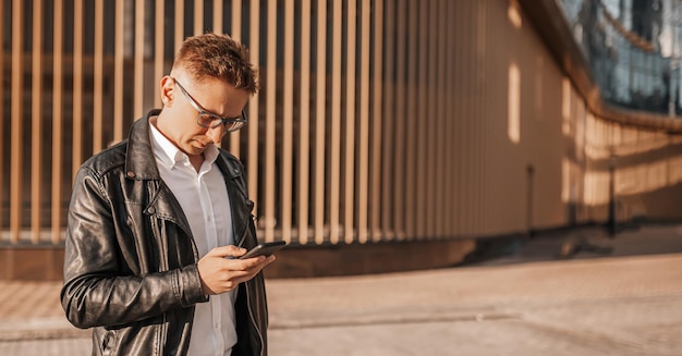 Knappe man met bril met een smartphone op straat van een grote stad Zakenman praten aan de telefoon op stedelijke achtergrond