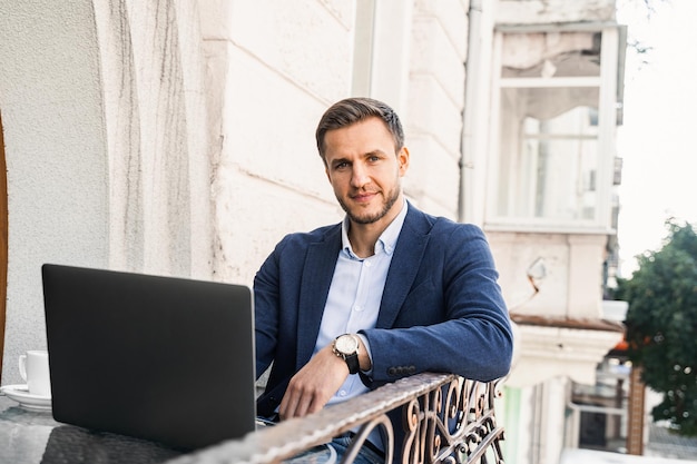 Knappe man met kopje koffie werkt online met behulp van laptop in café. Afstandswerk.