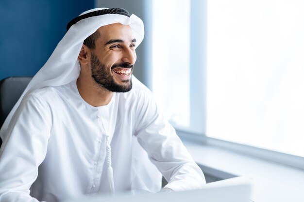 Knappe man met schotel dasha aan het werk in zijn kantoor in Dubai