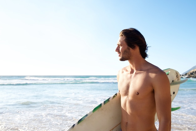 Knappe man met surfplank op het strand