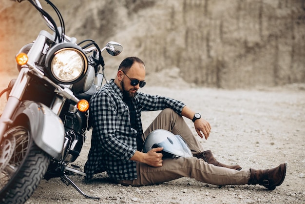 Knappe man met zijn moto in zandgroeve