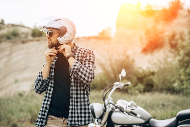 Knappe man met zijn moto in zandgroeve