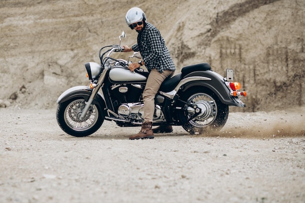 Knappe man met zijn moto in zandgroeve