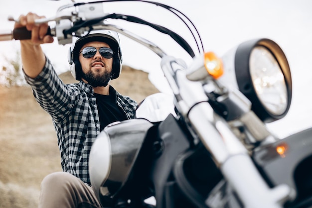 Knappe man met zijn moto in zandgroeve