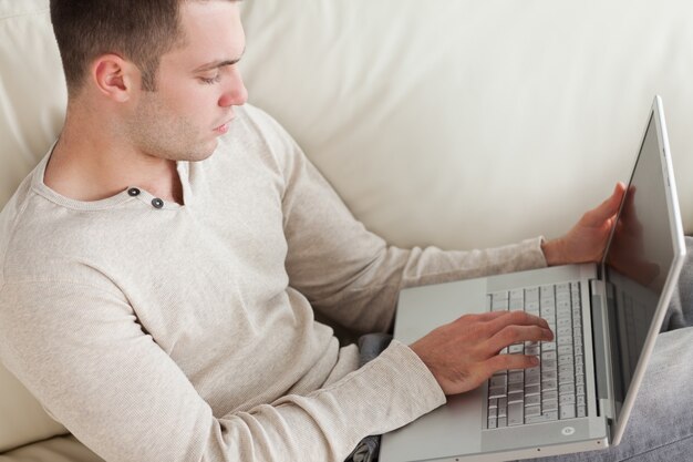 Knappe man ontspannen met een laptop in zijn woonkamer